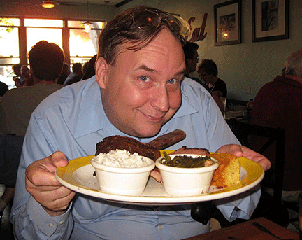 A smiling man holds plate of food