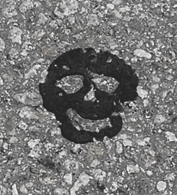A pattern in pavement tar resembles a face