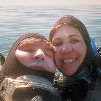 A couple in SCUBA gear float together in the ocean