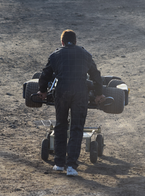 Man pushing gokart on wheeled cart